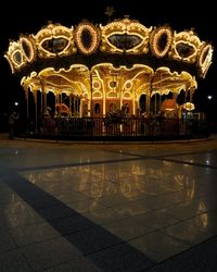 Illuminated carousel in amusement park at night