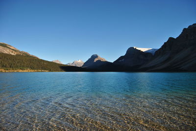 Scenic view of lake and mountains against clear blue sky