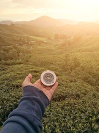 Cropped hand holding navigational compass on land