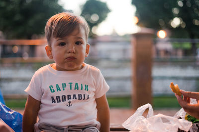Portrait of cute baby boy eating food while sitting outdoors