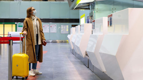 Woman with luggage waiting at airport check-in counter