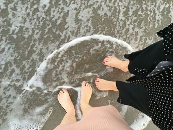 Low section of woman with umbrella on sea shore