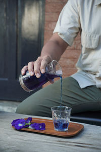 Midsection of woman drinking glass on table