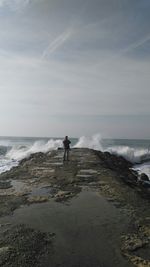 Rear view of man standing on pier against sky