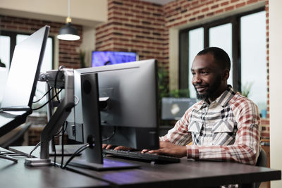 Happy young man using computer in office