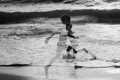 Double exposure of boy running at beach