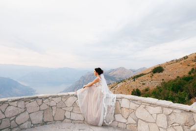 Rear view of woman standing on mountain against sky