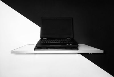 Close-up of laptop on table against wall