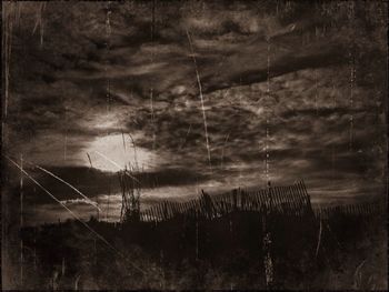 Power lines against cloudy sky