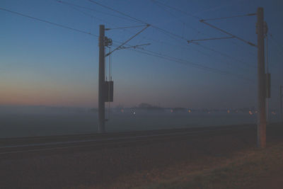 Power lines against sky at sunset