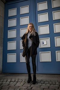 Portrait of young woman standing against wall