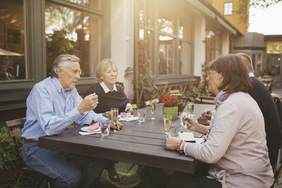 Two senior couples having desserts at outdoor restaurant