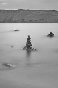 Stack of rocks in lake against sky