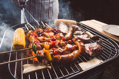 Midsection of man preparing food on barbecue grill