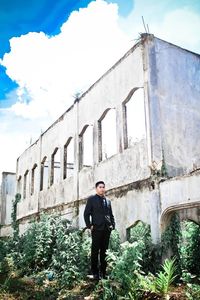 Full length portrait of young man standing against sky