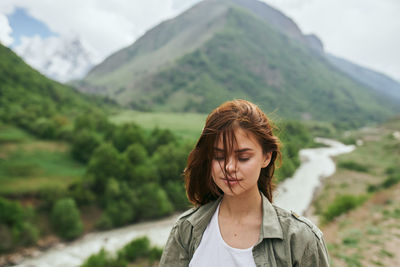 Portrait of young woman standing against mountain