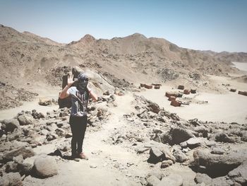 Rear view of man photographing woman standing on rock