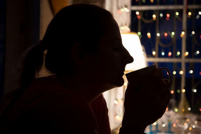 Silhouette woman drinking coffee while sitting at home