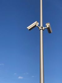 Low angle view of surveillance camera against blue sky