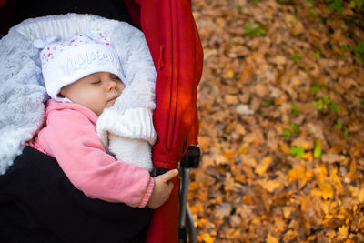 Cute baby girl sleeping in carriage over autumn leaves