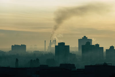 Smoke emitting from factory against sky during sunset