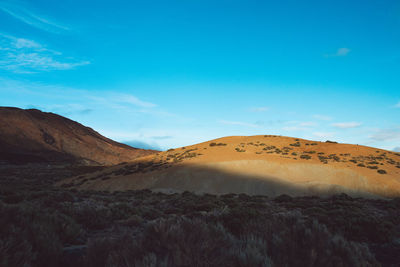 Scenic view of desert against blue sky