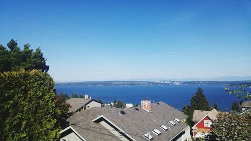 Houses by sea against clear blue sky