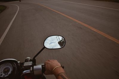 Cropped hand riding motorcycle on road