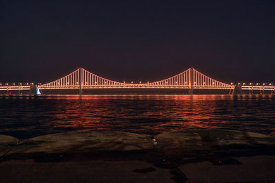 Golden gate bridge over sea against sky at night