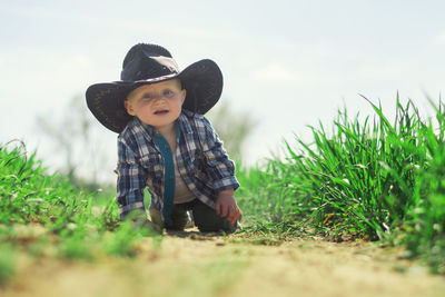 Cute boy wearing hat on field against sky