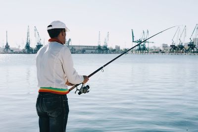 Rear view of man fishing in water