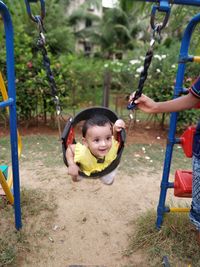 Cheerful baby girl on swing at playground