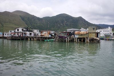 Houses by river and buildings against sky