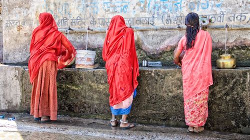 Rear view of women standing against red wall