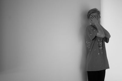 Woman hiding behind wall against white background