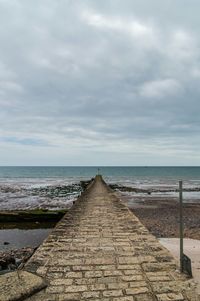 Pier on sea against cloudy sky