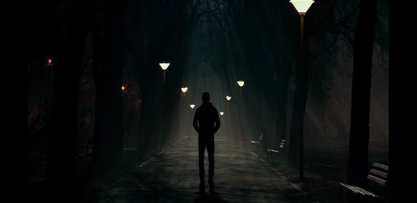Silhouette man standing on footpath at night