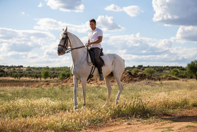 Man sitting on horse against sky