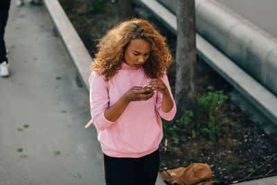 High angle view of woman text messaging on mobile phone at skateboard park