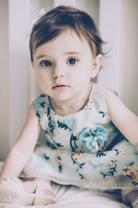 Portrait of cute baby girl sitting at home