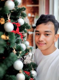 Portrait of smiling woman holding christmas tree