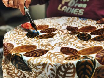 Midsection of woman making batik design on fabric in workshop