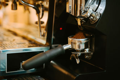 Pile of fresh ground coffee in portafilter placed in modern coffee machine at counter in cafe