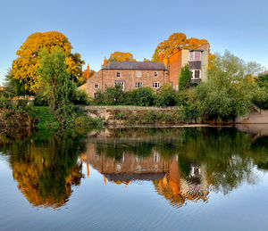 Reflection of trees and building in lake against sky