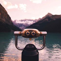 Close-up of coin-operated binoculars against mountains