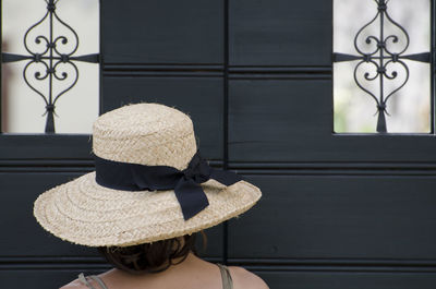 Rear view of woman in hat standing against closed door