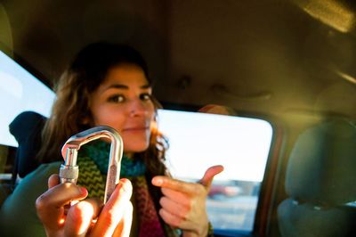 Portrait of young woman showing carabiner in car