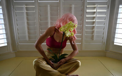 Full length of woman sitting by window at home