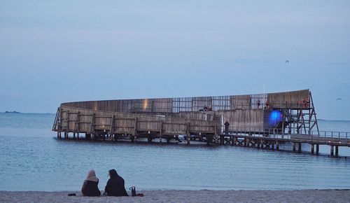 People on beach against clear sky