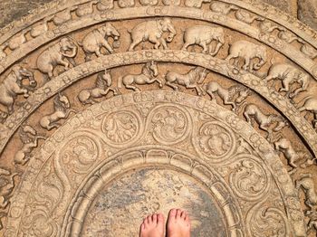 Low section of person standing by carvings